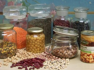 Une photo qui montre de différentes variétés de fèves, lentilles et pois chiches, sèchés, en bocaux ou en conserves.